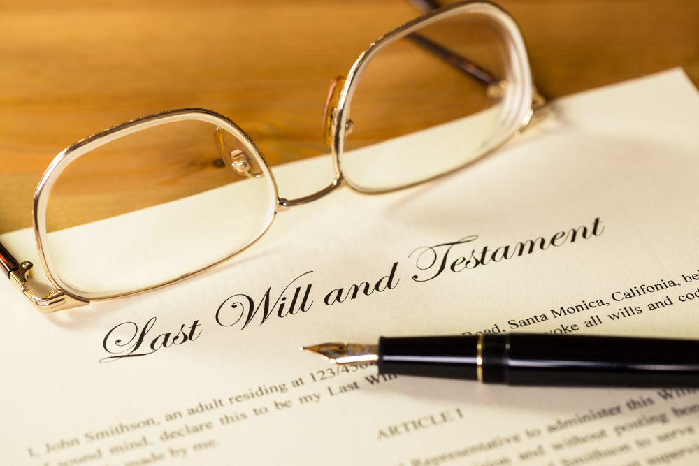 A pen and glasses sitting on top of a last will.