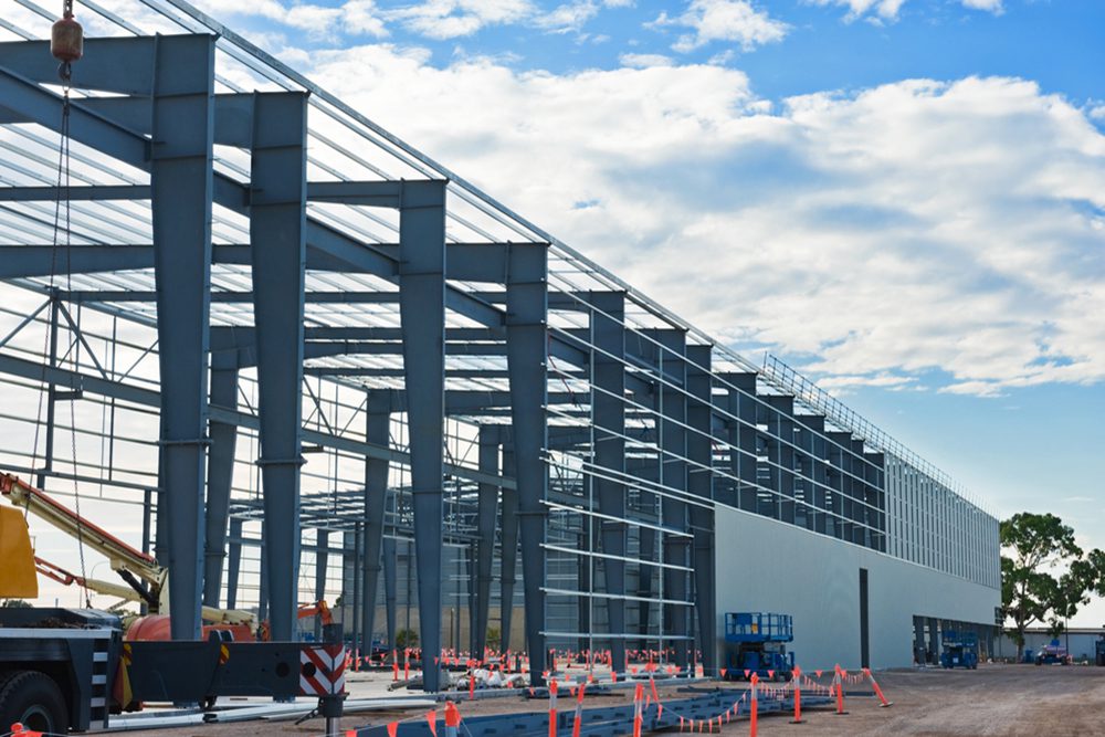 A building under construction with orange cones around it.